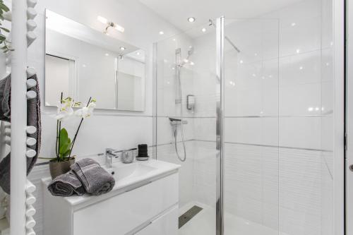 une salle de bain blanche avec une douche et un lavabo dans l'établissement Le CRISTAL Port Ambonne Village Naturiste, au Cap d'Agde