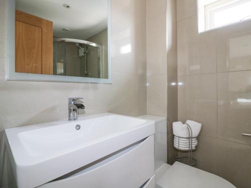 a white bathroom with a sink and a toilet at Cormorant in Holywell Bay