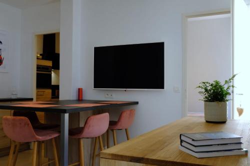 un salon avec une table et une télévision sur un mur dans l'établissement Modern Flat In The Heart Of Chamonix, à Chamonix-Mont-Blanc