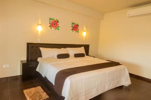 a bedroom with a large white bed with flowers on the wall at Urqu Hotel & Boutique in Jaén