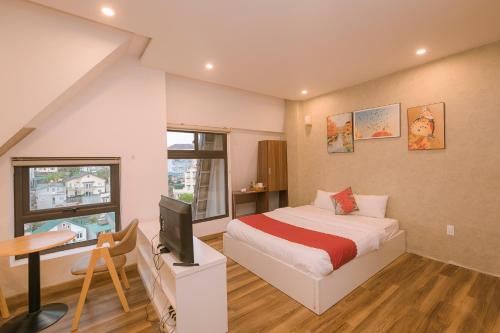 a bedroom with a bed and a desk with a television at Ngan Pho Studio & Hotel in Da Lat