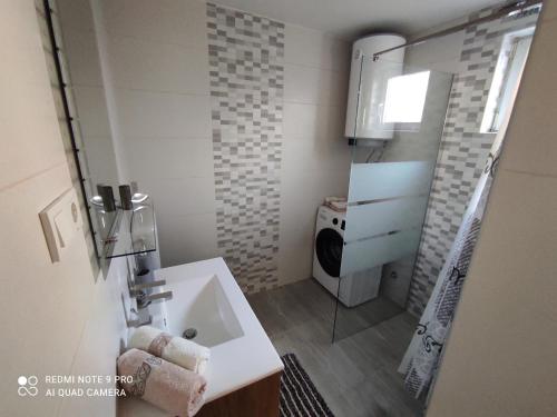 a bathroom with a sink and a washing machine at Holiday House Santa in Lopar