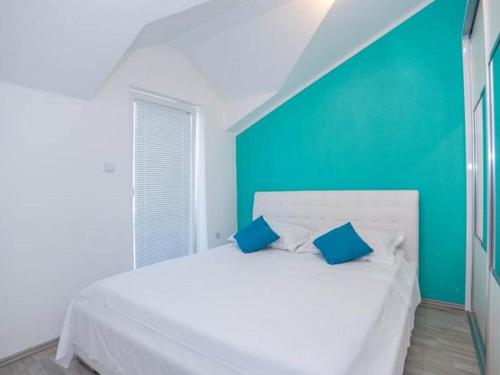 a bedroom with a white bed with a blue wall at Apartment Sanja in Povlja