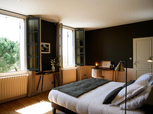 a bedroom with a large bed and two windows at Clos des Jacobins (Grand Cru Classé) in Saint-Émilion