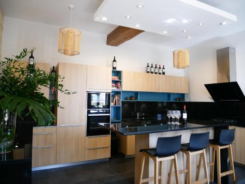 a kitchen with wooden cabinets and blue bar stools at Clos des Jacobins (Grand Cru Classé) in Saint-Émilion