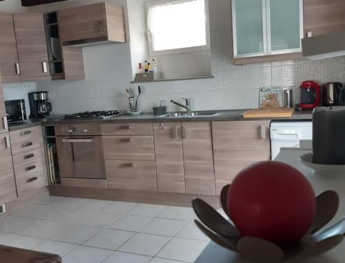 una cocina con armarios de madera y un cuenco rojo sobre una mesa en Maison Le Grès Rose, en Erquy