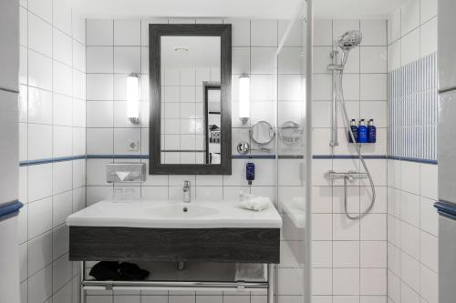 a white bathroom with a sink and a mirror at MERCURE KLAIPEDA CITY HOTEL, Meetings, Events, Restaurant & Bar - Accor Group, Pet Stay FREE in Klaipėda