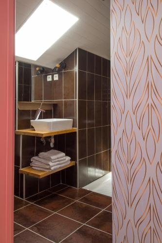 La salle de bains est pourvue d'un lavabo et de carreaux bruns. dans l'établissement Villa La Muse, à Mostuéjouls