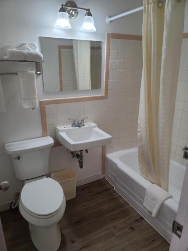 a bathroom with a toilet and a sink and a tub at Sunset Motel Santa Rosa, NM in Santa Rosa