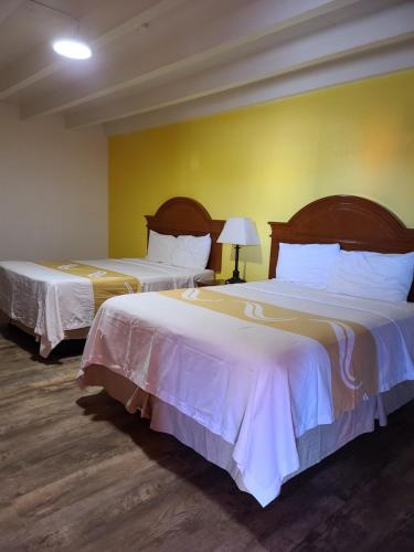 a hotel room with two beds and a yellow wall at Sunset Motel Santa Rosa, NM in Santa Rosa