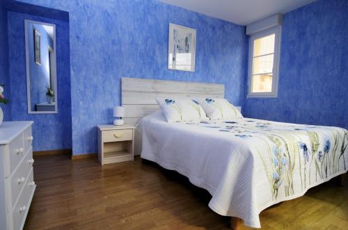 - une chambre bleue avec un lit et un mur bleu dans l'établissement Le domaine de l'Escadasse, à Faycelles