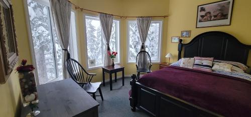 a bedroom with a bed and a table and windows at Vacation Homes by The Bulldog- Berker's Suite A in Silver Star