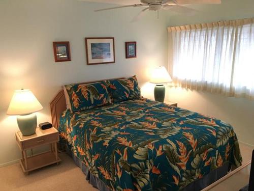 a bedroom with a bed and two lamps and a window at Wailua Bay View Resort in Kapaa
