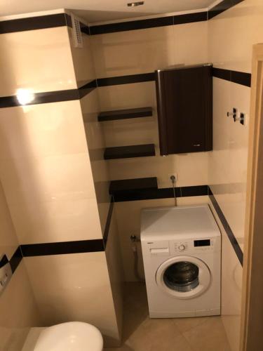 a small bathroom with a toilet and a washing machine at Apartament Tuwima 8 in Ełk