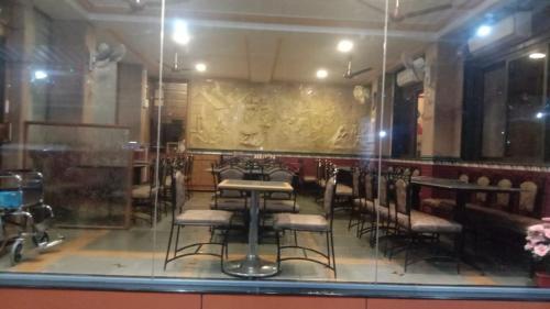 a dining room with tables and chairs behind a glass window at Kuber's Residency in Mahad