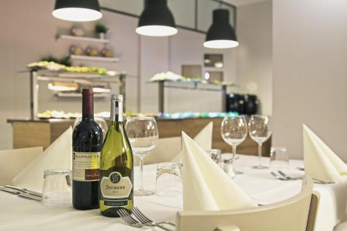 two bottles of wine sitting on a table with glasses at Biker Hotel Al Gallo Forcello in Passo Pramollo