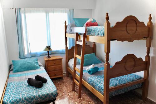 クリェラにあるApartamento en la playa Arensol Culleraのベッドルーム1室(二段ベッド2台、窓付)が備わります。