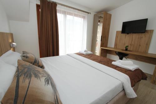 a hotel room with a large white bed and a television at Baron in Budva