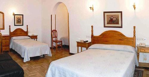 a hotel room with two beds and a chair at Hostal Maria Cristina in Madrid
