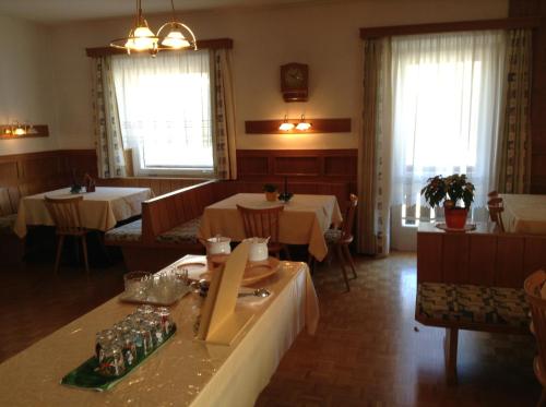 uma sala de jantar com duas mesas e cadeiras e janelas em Garni Hofer em Sesto