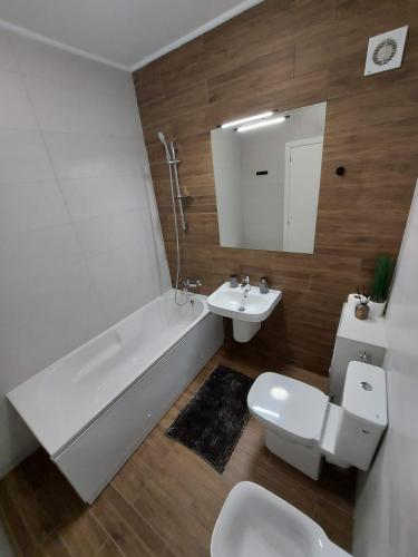 a bathroom with a tub and a toilet and a sink at Panoramic Apartments Oradea in Oradea