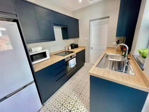 a kitchen with blue cabinets and a sink at The Balmoral close to the racecourse in York