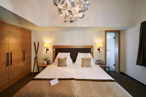 a bedroom with a large bed and a chandelier at Hotel Ambiance Superior in Zermatt