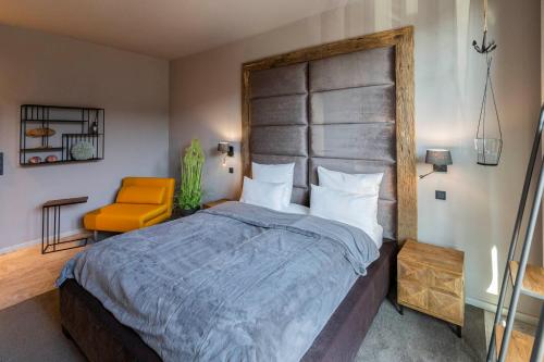 a bedroom with a large bed and a orange chair at Port of Travemünde, Opening 2021 in Travemünde