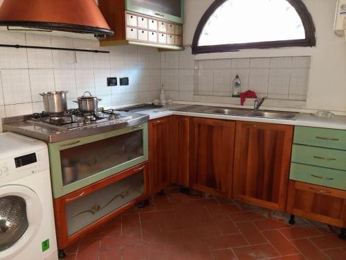 a kitchen with a stove and a sink and a washing machine at Casa La Fornace in Fornacette