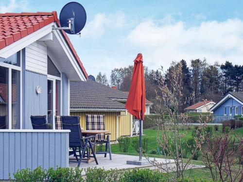 un patio con una sombrilla roja junto a una casa en 4 person holiday home in GROEMITZ, en Grömitz