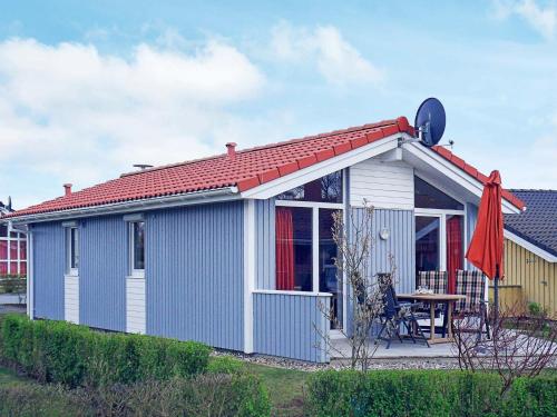 una pequeña casa azul y blanca con techo rojo en 4 person holiday home in GROEMITZ, en Grömitz