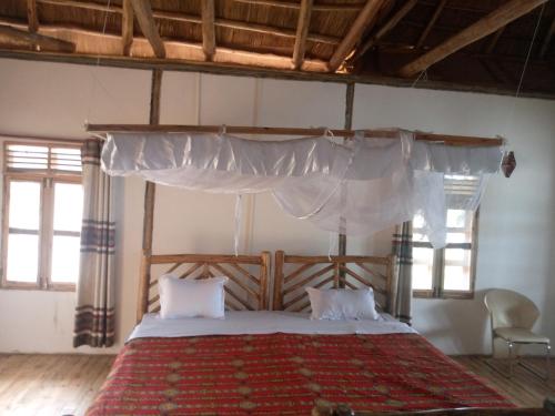 a bedroom with a large bed with a canopy at Tembo Safari Lodge in Katunguru