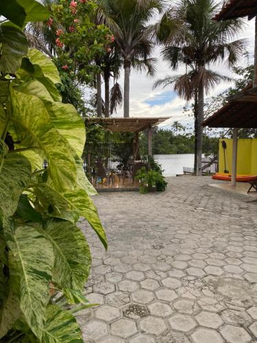 a stone walkway with palm trees and a pavilion at Chalé Marinas in Barreirinhas