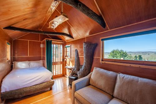 坎特伯雷的住宿－Oakside Tree Tops，一间卧室配有一张床、一张沙发和一个窗口