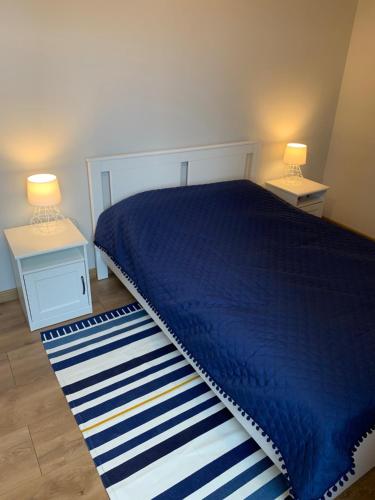 a bedroom with a blue bed and two night stands at Kapitański Hel in Hel