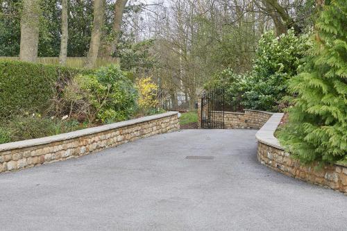 a garden with a stone retaining wall and a driveway at Host & Stay - The Old Rectory in Witton Gilbert