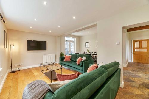 a living room with a green couch and a tv at Host & Stay - The Old Rectory in Witton Gilbert