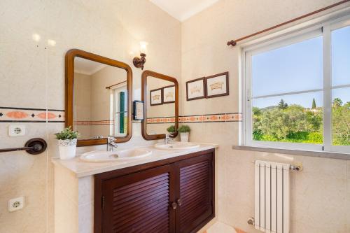 a bathroom with two sinks and a window at Quinta das Figueiras - Bordeira - Faro in Bordeira