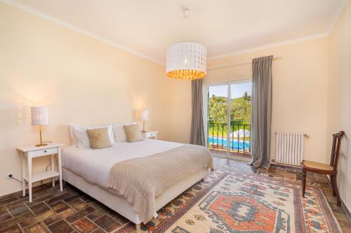 a bedroom with a bed and a large window at Quinta das Figueiras - Bordeira - Faro in Bordeira