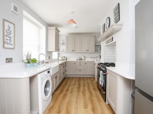 a white kitchen with a washer and dryer at Lluest in Beaumaris