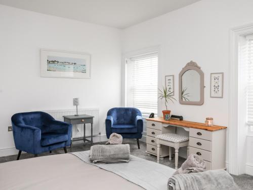 a bedroom with two blue chairs and a desk at Lluest in Beaumaris