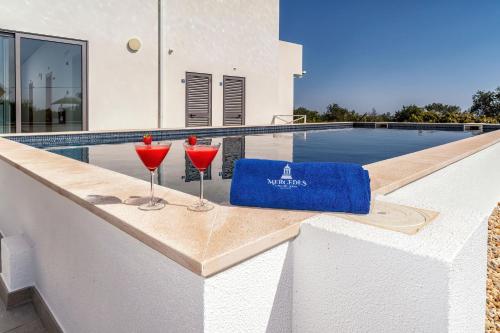 two glasses of wine on a ledge next to a swimming pool at Mercedes Country House in Faro