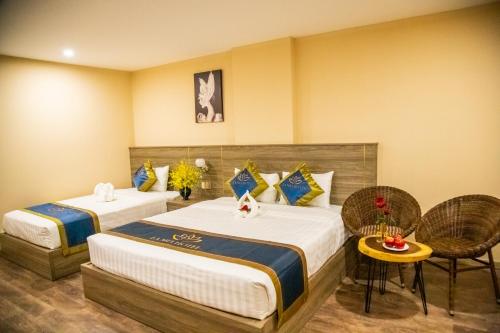 a hotel room with two beds and a table and chairs at LA MIA Lakeview Hotel in Pleiku