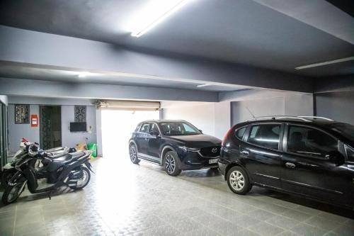 two cars and a motorcycle parked in a garage at LA MIA Lakeview Hotel in Pleiku