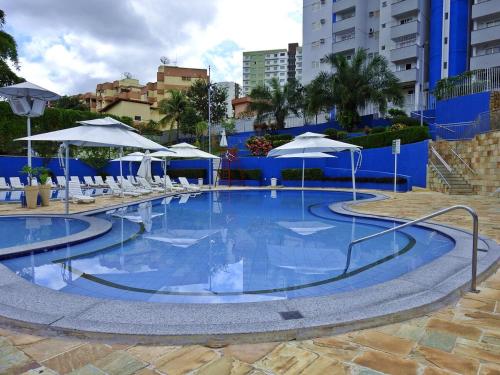 a large swimming pool with chairs and umbrellas at Residencial Thermas Caldas in Caldas Novas