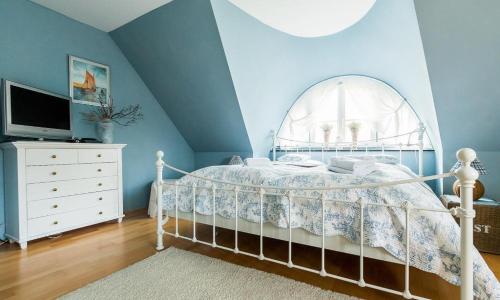 a bedroom with a white bed and a blue wall at Skipperhus in Ahrenshoop