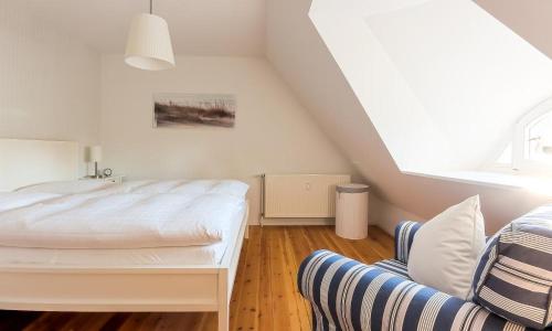 1 dormitorio blanco con 1 cama y 1 silla en Landhaus Butt 05, en Ahrenshoop