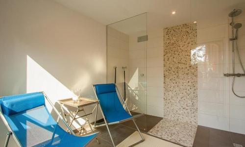 a bathroom with two blue chairs and a glass shower at Strandhaus Hühnergott in Neuhaus