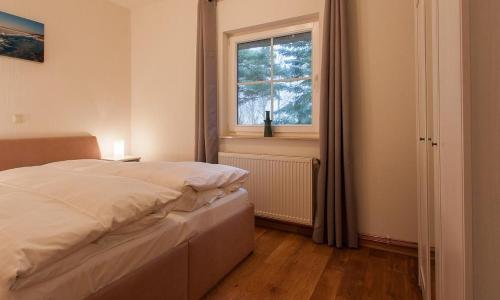 a bedroom with a white bed and a window at Haus Schilfkante - Wohnung 2 in Wieck