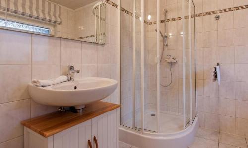 a white bathroom with a sink and a shower at Haus Schilfkante - Wohnung 2 in Wieck